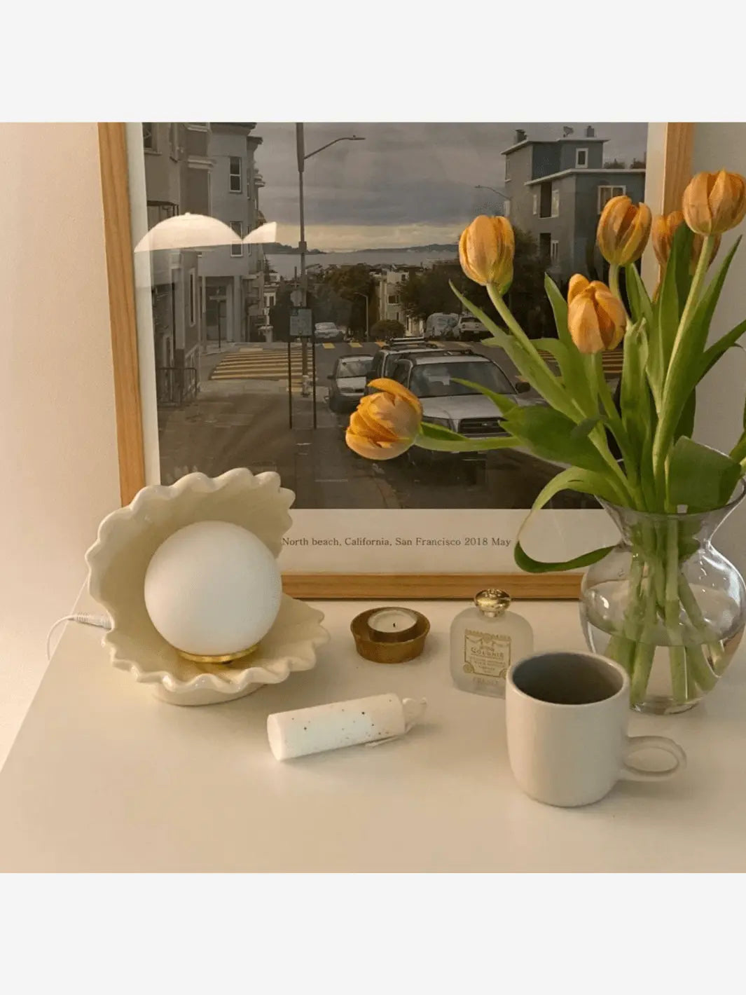 lampe de chevet en ceramique en forme de coquillage qui s ouvre sur une perle qui s allume design moderne sur un bureau a cote d un pot de fleurs