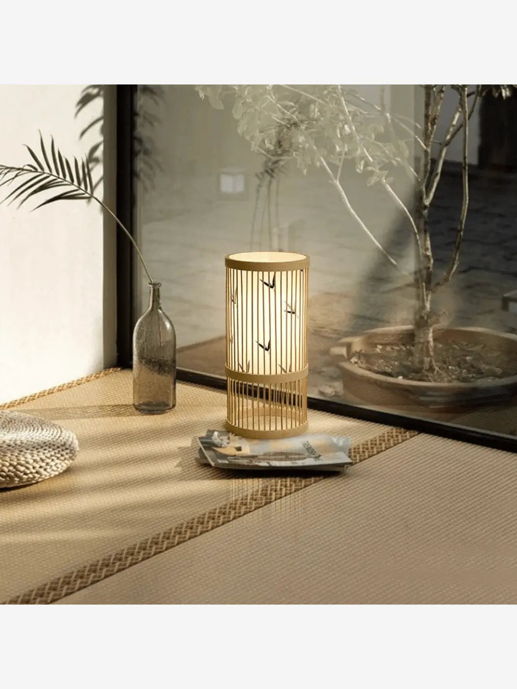 lampe de chevet en bambou a motifs oiseaux style japonais dans un decor beige et olive avec un olivier en fond