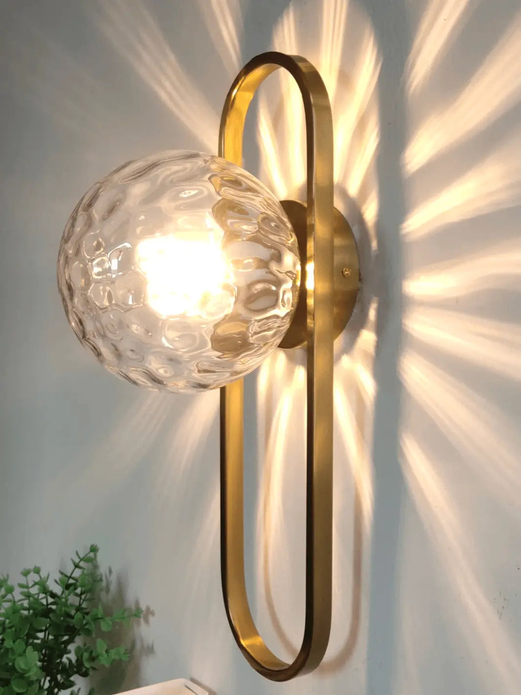 lampe de chevet murale doree a la forme originale avec une boule transparente eclatante