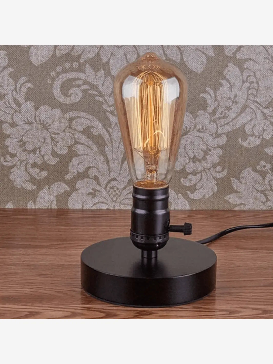 lampe de chevet industrielle noire avec une ampoule incandescence posee sur une table en bois