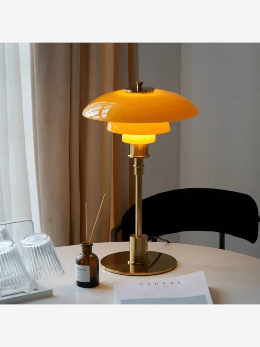 lampe de chevet metal champignon or et orange posee sur une table a manger blanche