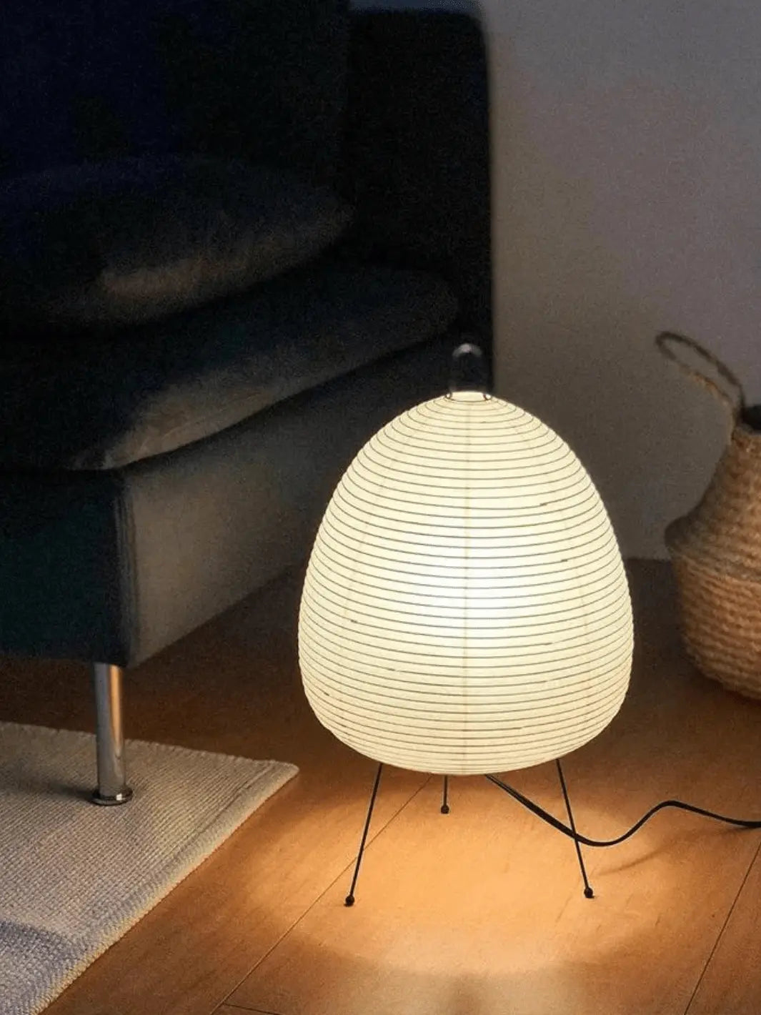 lampe de chevet sur pied noir avec abat jour en papier de riz style japonais posee au sol dans un salon moderne